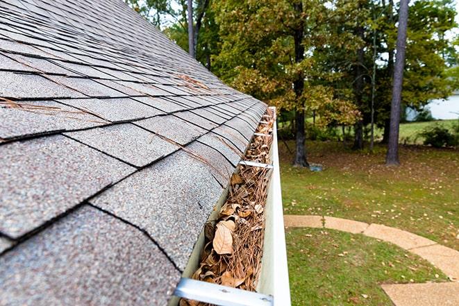 a gutter being cleared of leaves and twigs